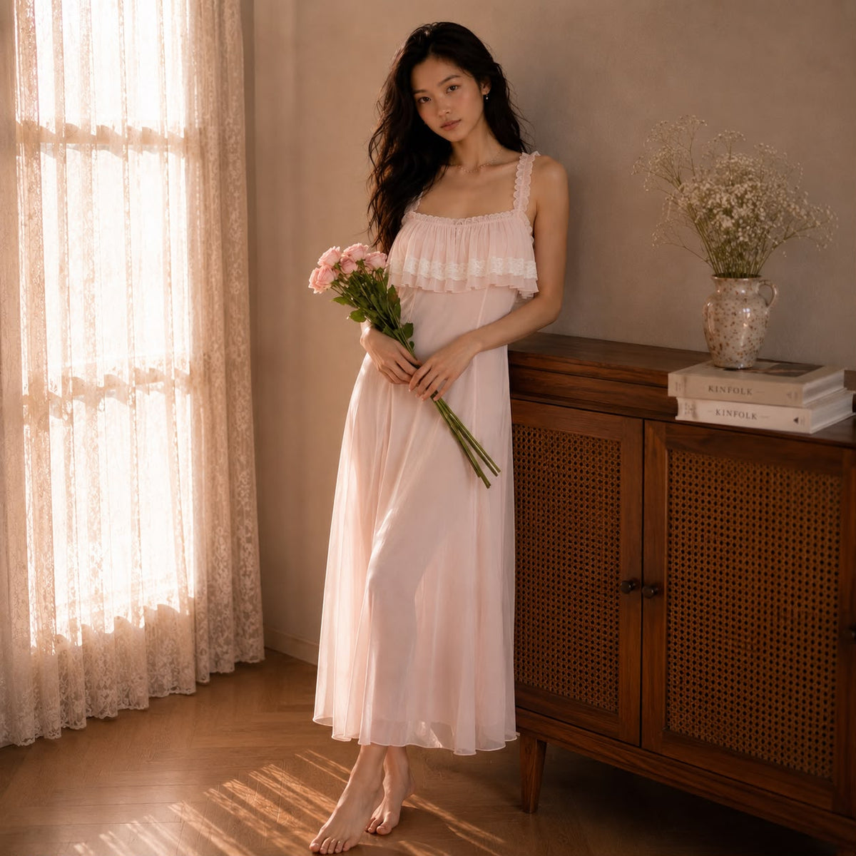 Aurelia Slip Dress - Blush Pearl, standing full-length by window showing fluid mesh drape and ruffle bust detail